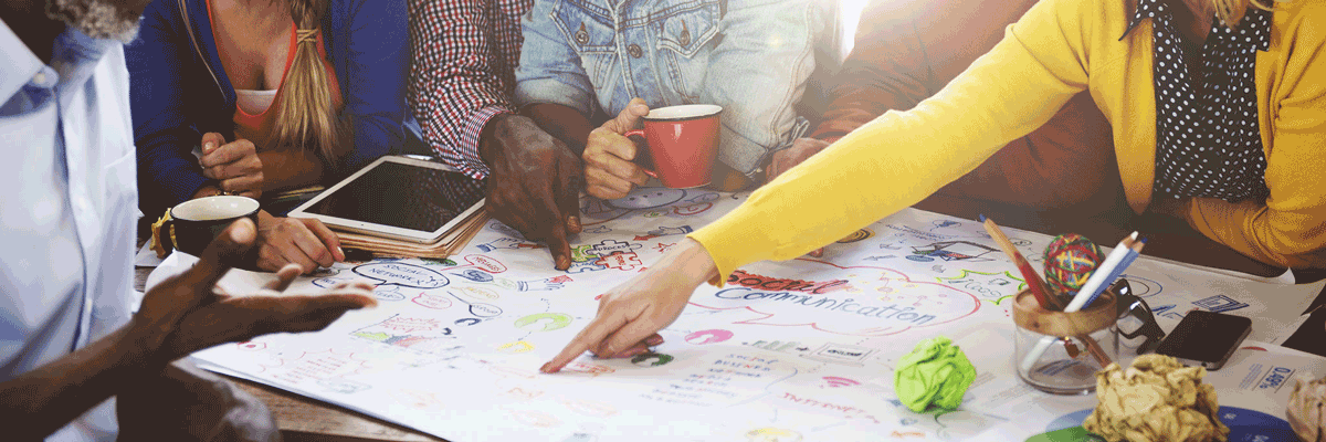 Webdesign Werdern - Designteam sitzt um einen Tisch auf dem ein großes Blatt Papier mit einer Mindmap liegt.